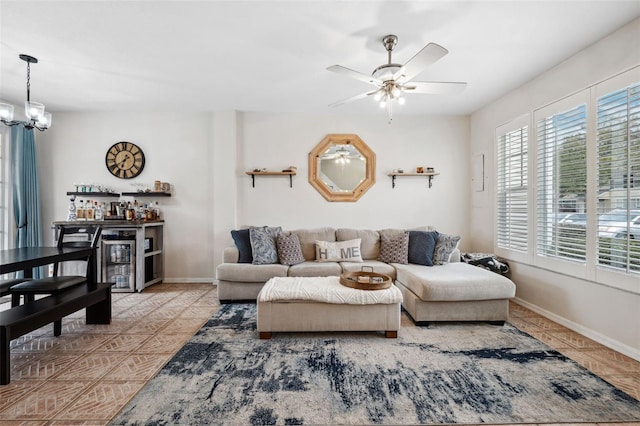 living room with light tile patterned flooring, indoor bar, and ceiling fan with notable chandelier