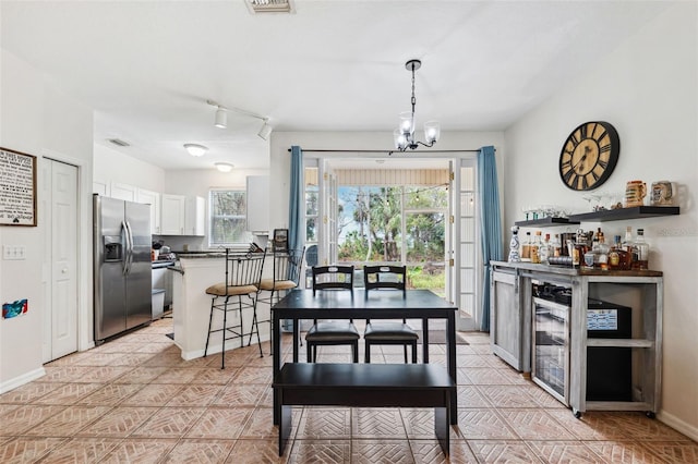 dining space with light tile patterned floors, indoor bar, and a notable chandelier