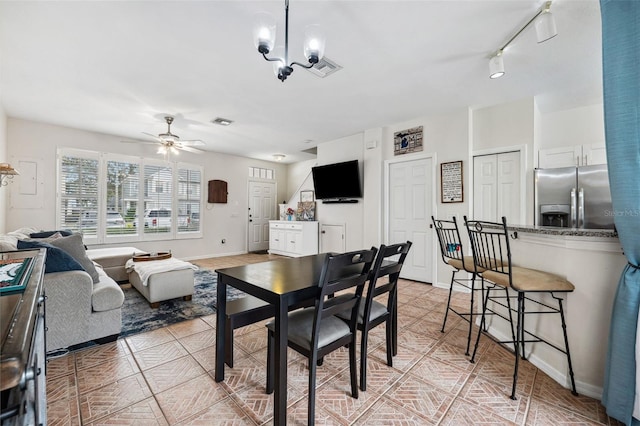 dining room with light tile patterned floors, ceiling fan with notable chandelier, and track lighting