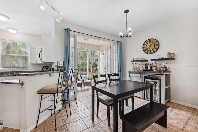 dining room with sink, a notable chandelier, and beverage cooler