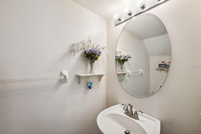 bathroom featuring a textured ceiling, lofted ceiling, and sink