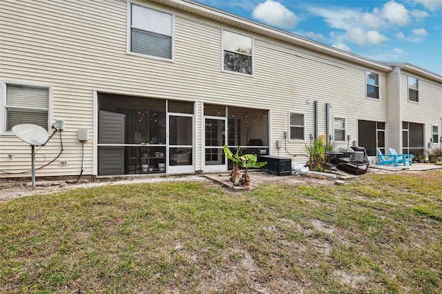 back of property with a sunroom, a lawn, and a patio