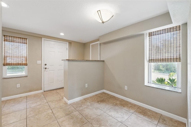 unfurnished room featuring light tile patterned floors, baseboards, and a wealth of natural light