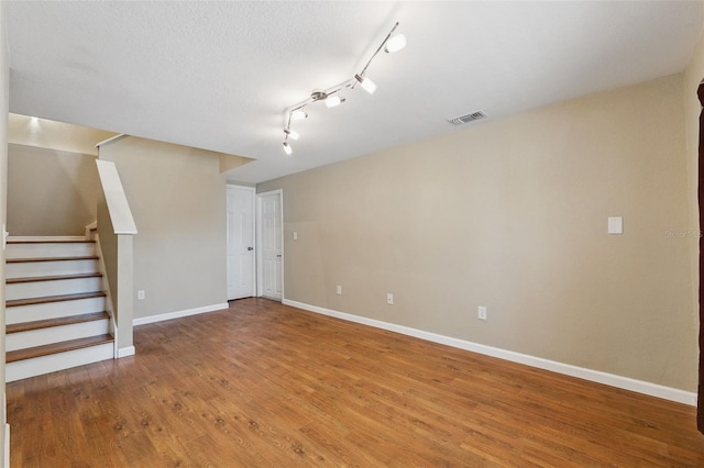interior space featuring visible vents, track lighting, baseboards, stairway, and light wood-style floors
