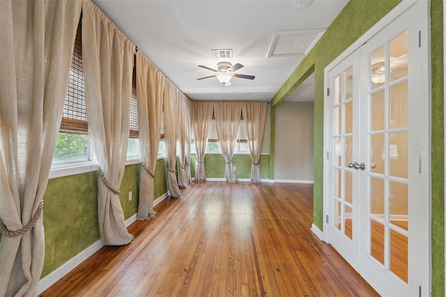 spare room featuring french doors, hardwood / wood-style floors, a healthy amount of sunlight, and visible vents