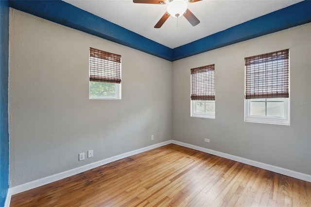 unfurnished room featuring hardwood / wood-style floors, a ceiling fan, and baseboards