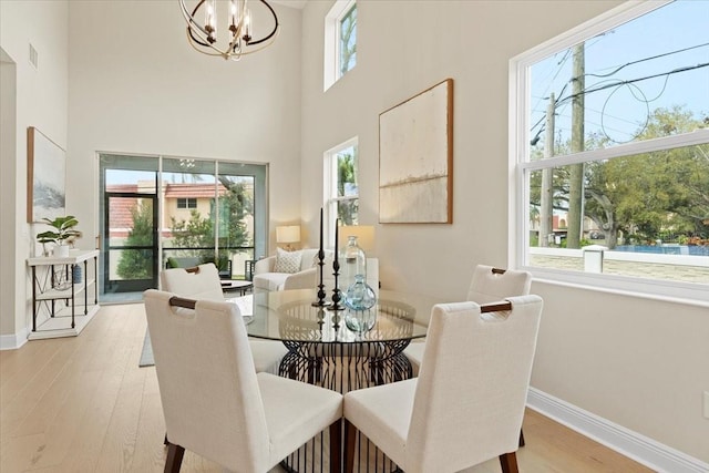 dining room featuring a high ceiling, light hardwood / wood-style flooring, and a notable chandelier