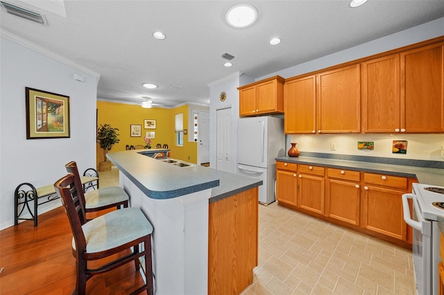 kitchen featuring crown molding, white appliances, a breakfast bar area, and a kitchen island