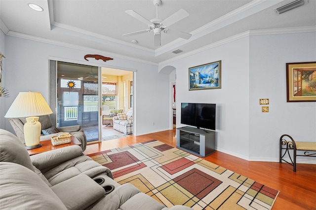 living room with ceiling fan, hardwood / wood-style floors, crown molding, and a raised ceiling