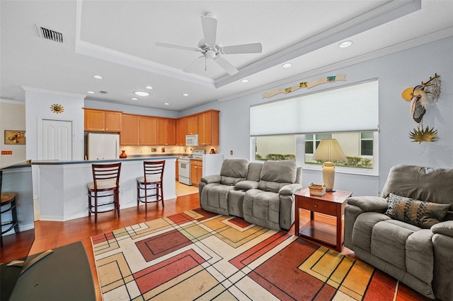 living room featuring ceiling fan, crown molding, light hardwood / wood-style flooring, and a raised ceiling