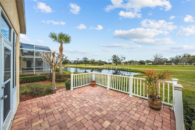 view of patio with glass enclosure and a water view