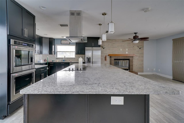 kitchen with decorative light fixtures, light stone countertops, stainless steel appliances, and tasteful backsplash