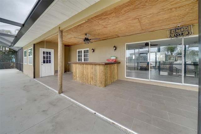 view of patio / terrace with ceiling fan, a lanai, and exterior bar