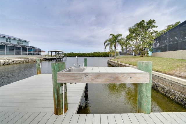 dock area featuring a lanai, a water view, a lawn, and sink