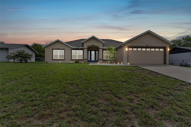 ranch-style home featuring a lawn and a garage