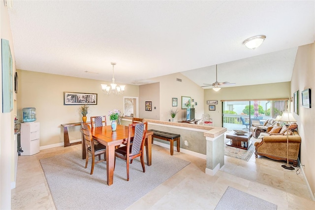 dining area featuring ceiling fan with notable chandelier and vaulted ceiling