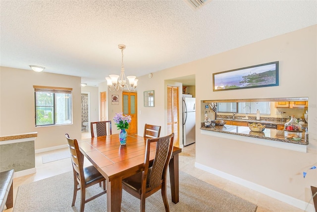 dining area with sink, an inviting chandelier, light tile patterned floors, and a textured ceiling