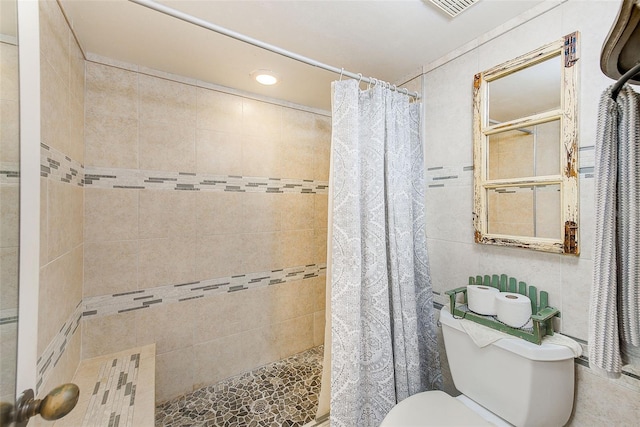 bathroom featuring toilet, walk in shower, and tile walls