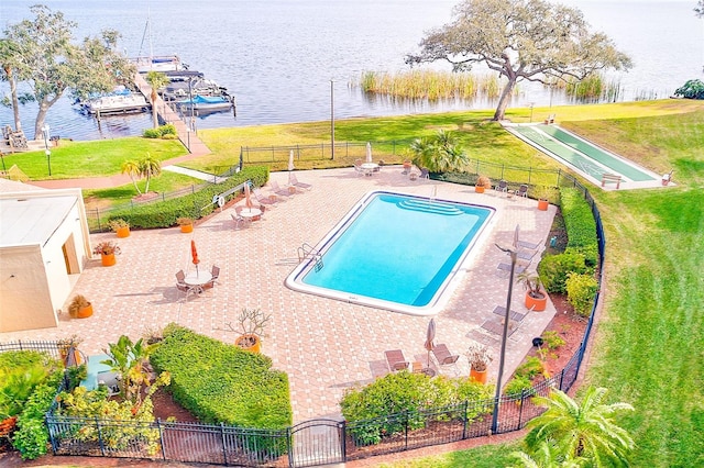 view of swimming pool featuring a water view, a lawn, and a patio area