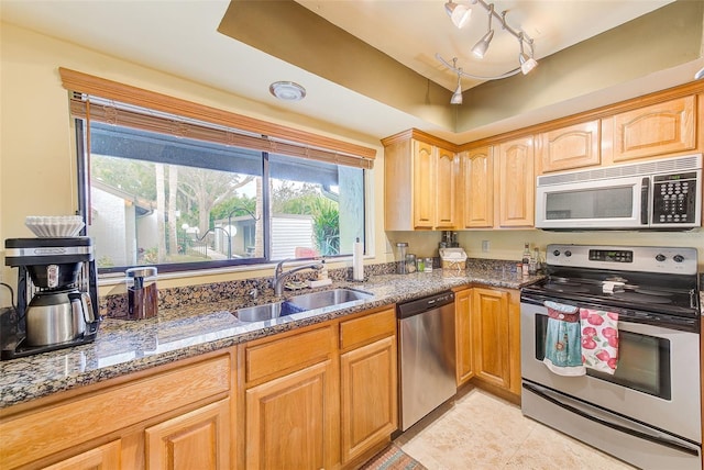 kitchen featuring stainless steel appliances, stone countertops, sink, and light tile patterned flooring