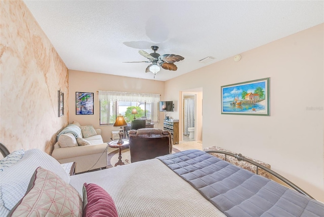 bedroom with ceiling fan, connected bathroom, and a textured ceiling