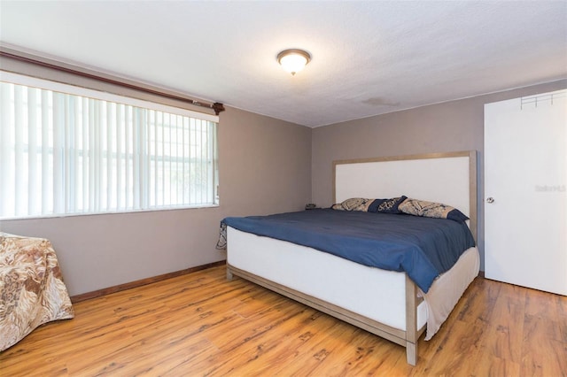 bedroom with a textured ceiling and light hardwood / wood-style floors