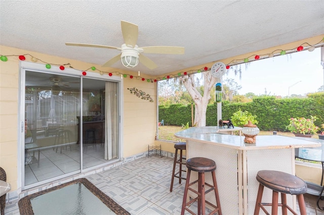 view of patio featuring ceiling fan and a bar