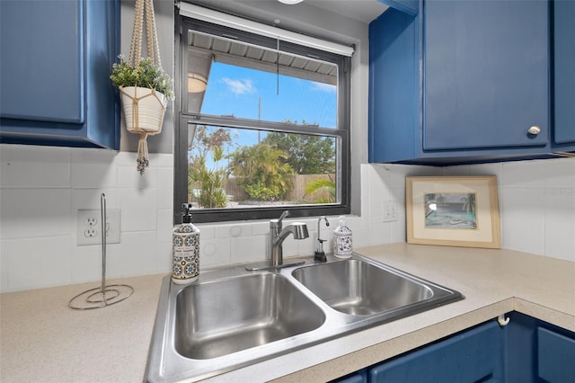 kitchen with backsplash, sink, and blue cabinetry