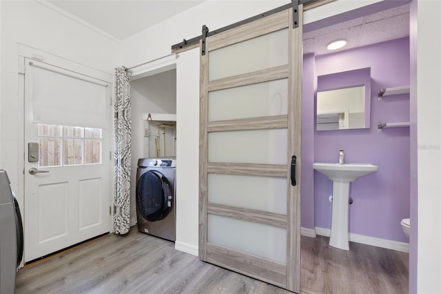 laundry room with light hardwood / wood-style floors, sink, a barn door, and washer / clothes dryer