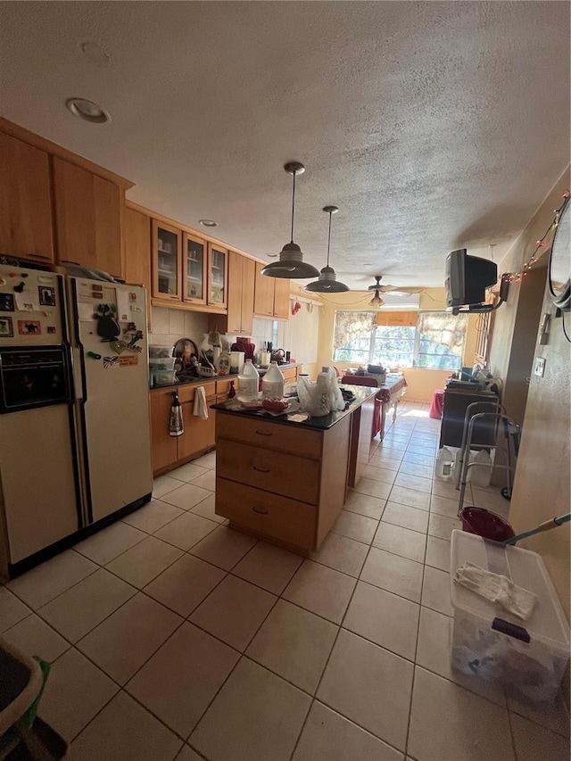 kitchen featuring light tile patterned flooring, white refrigerator with ice dispenser, a textured ceiling, and decorative light fixtures