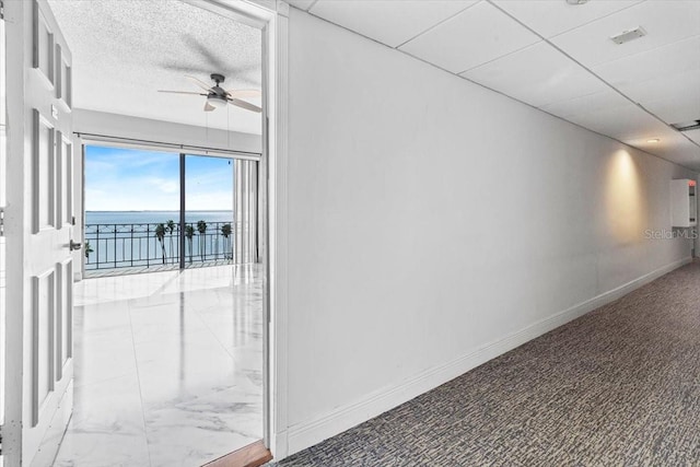 corridor with a water view and a textured ceiling