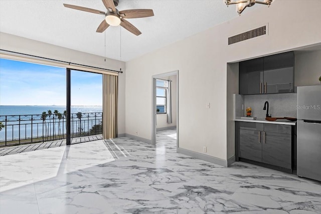 interior space with a water view, a healthy amount of sunlight, ceiling fan, and sink