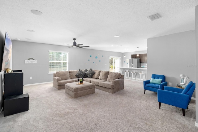 living room featuring light colored carpet, a textured ceiling, and plenty of natural light