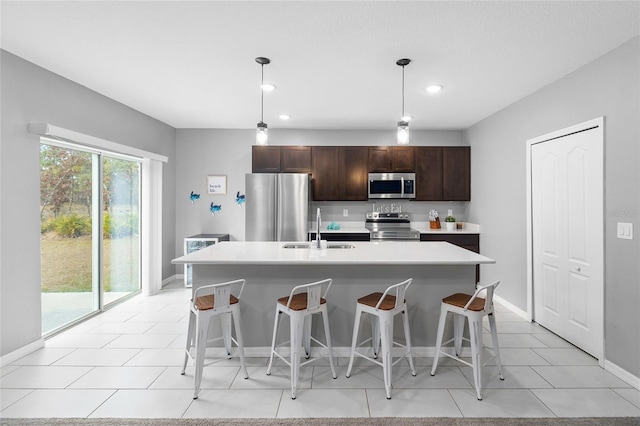 kitchen with appliances with stainless steel finishes, a center island with sink, decorative light fixtures, and sink