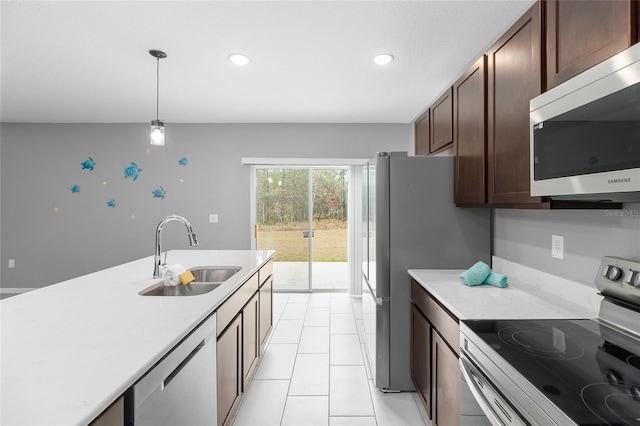 kitchen featuring appliances with stainless steel finishes, decorative light fixtures, sink, light tile patterned flooring, and dark brown cabinets