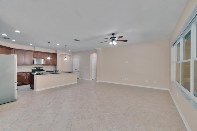 kitchen with sink, stainless steel appliances, decorative backsplash, a center island with sink, and decorative light fixtures