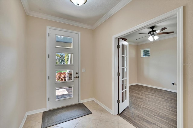 tiled foyer featuring crown molding and ceiling fan