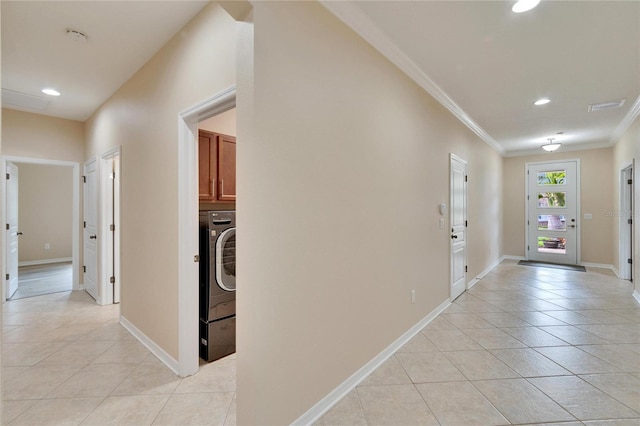 hallway with crown molding, washer / dryer, and light tile patterned floors