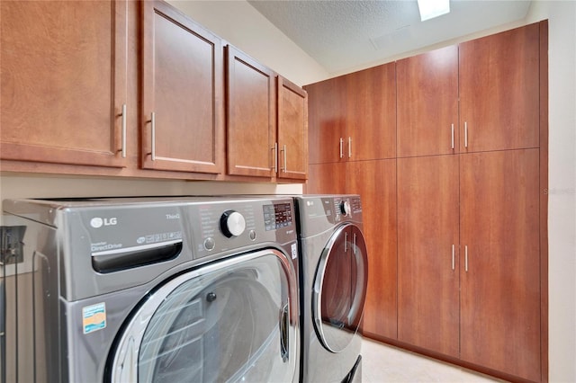 laundry room with washing machine and dryer, cabinets, and a textured ceiling