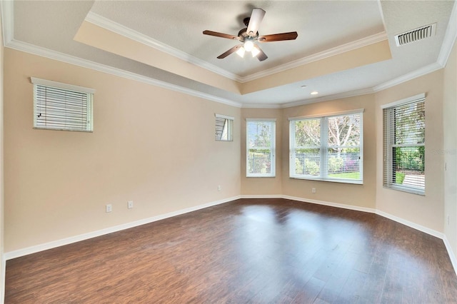 unfurnished room with ceiling fan, a wealth of natural light, dark hardwood / wood-style flooring, and a tray ceiling