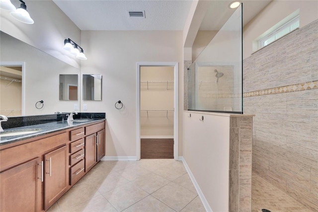 bathroom with vanity, tile patterned flooring, a textured ceiling, and a tile shower