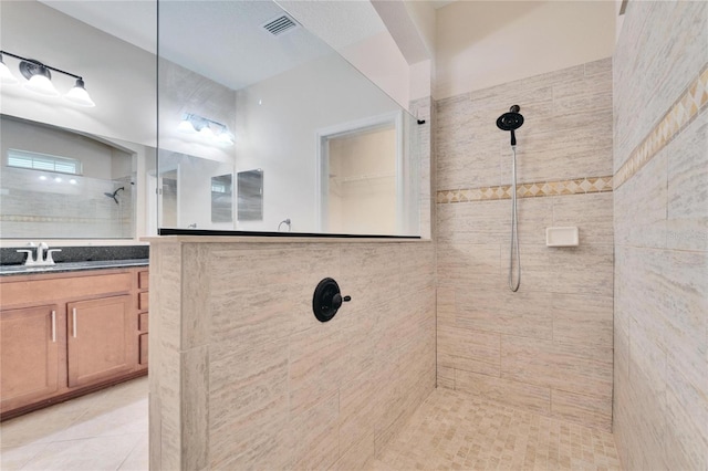 bathroom with tile patterned floors, vanity, and tiled shower