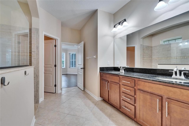 bathroom with tiled shower, vanity, tile patterned floors, and a textured ceiling