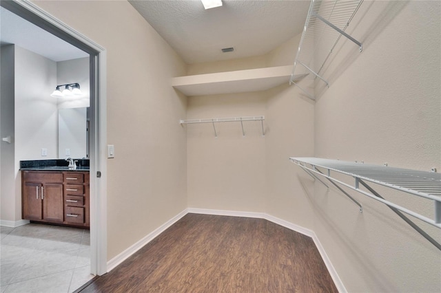 walk in closet with sink and light hardwood / wood-style floors