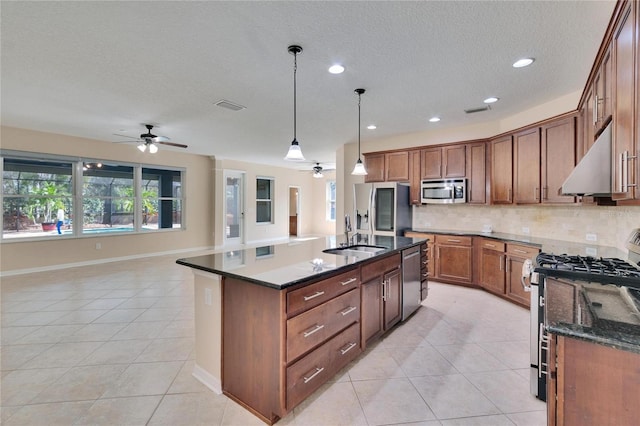 kitchen featuring pendant lighting, tasteful backsplash, sink, a kitchen island with sink, and stainless steel appliances