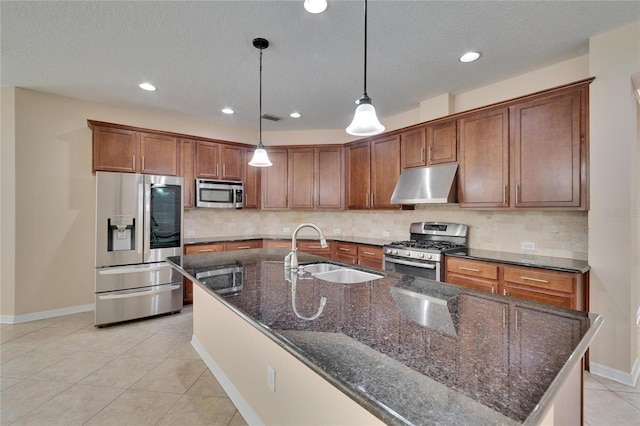 kitchen with sink, dark stone countertops, hanging light fixtures, stainless steel appliances, and tasteful backsplash