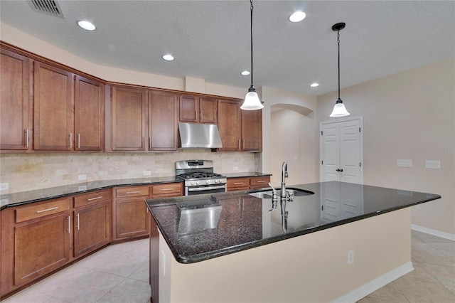 kitchen with sink, hanging light fixtures, stainless steel range with gas stovetop, and an island with sink