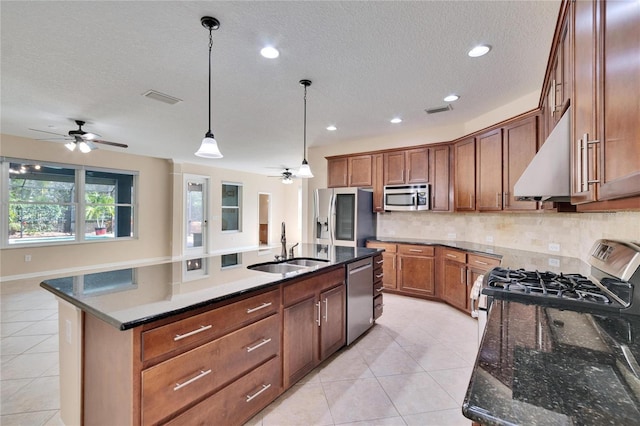 kitchen with appliances with stainless steel finishes, ventilation hood, sink, hanging light fixtures, and a center island with sink