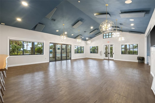 unfurnished living room with dark hardwood / wood-style flooring, high vaulted ceiling, an inviting chandelier, and french doors