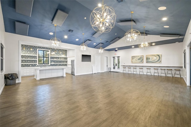 unfurnished living room featuring high vaulted ceiling, dark wood-type flooring, sink, and an inviting chandelier